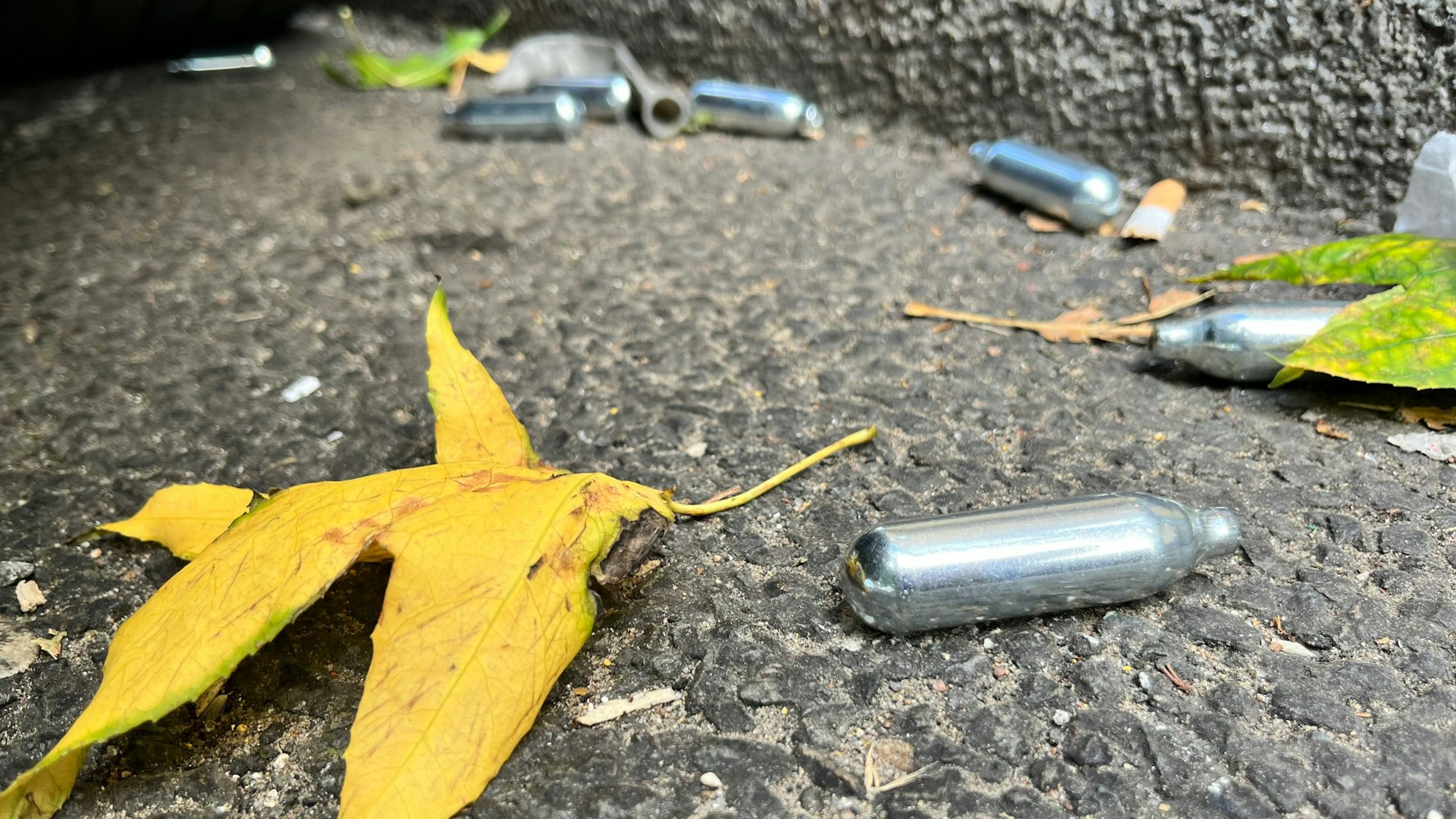 Auf einer Straße liegen mehrere Gaspatronen mit Lachgas.