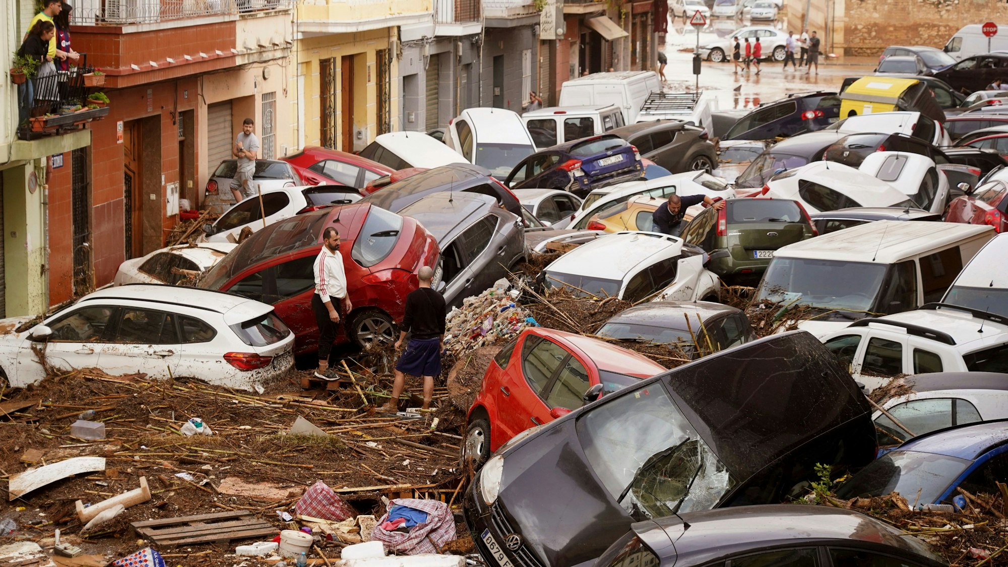 30.10.2024, Spanien, Valencia: Anwohner betrachten durch die Wassermassen aufgestapelte Autos. Foto: Alberto Saiz/AP +++ dpa-Bildfunk +++