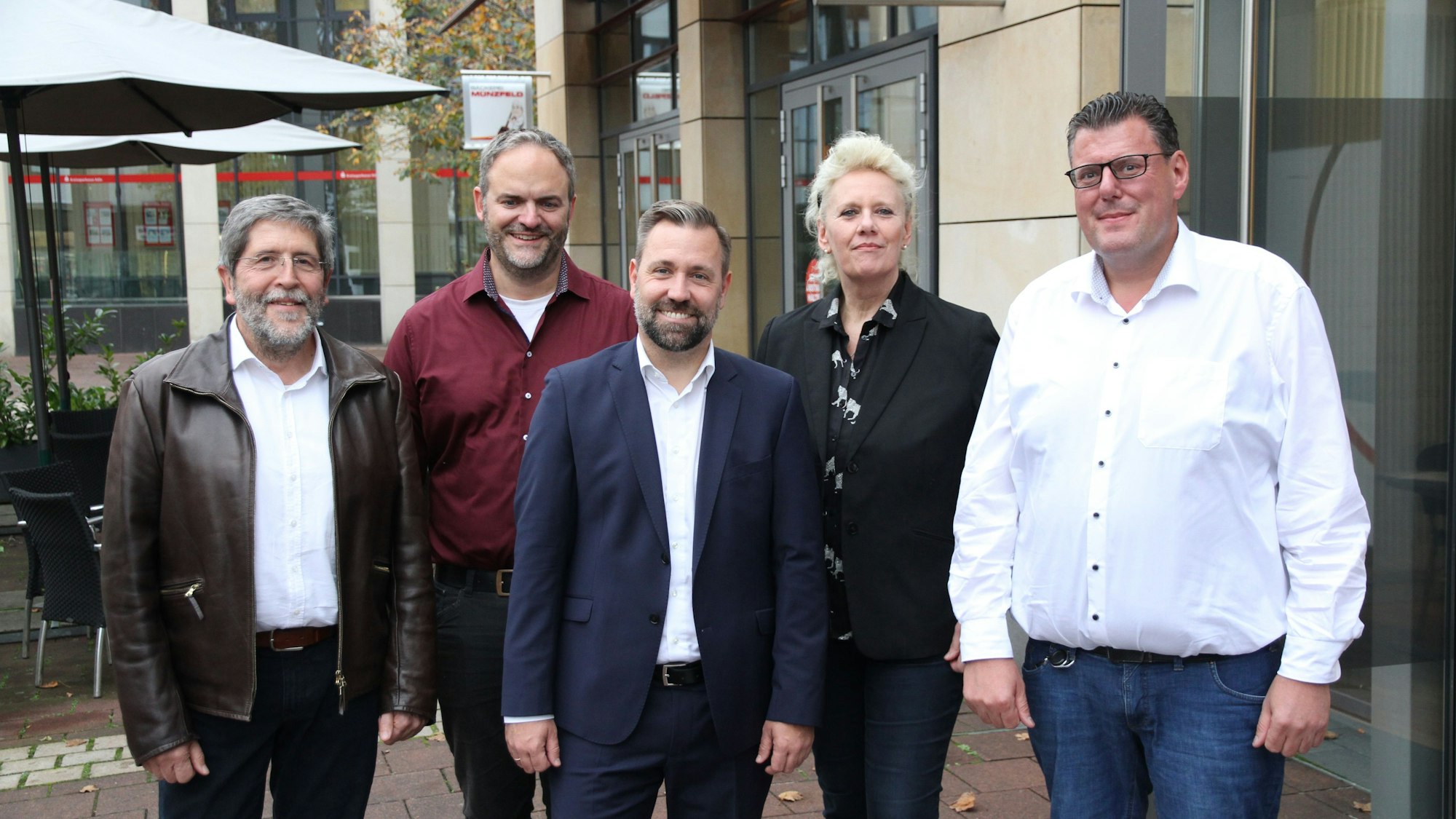 Vier Männer und eine Frau vor einem Gebäude