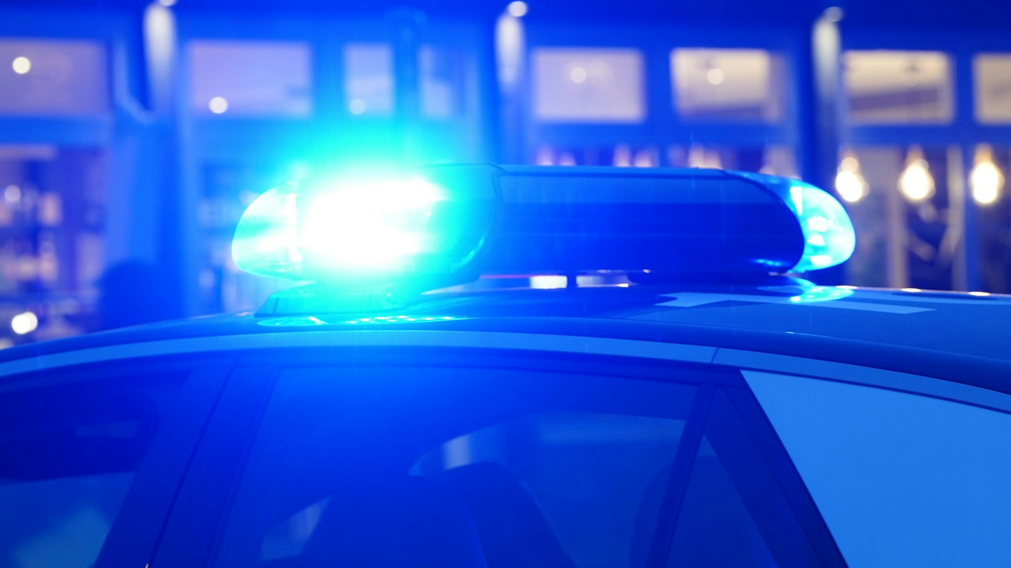 Ein Streifenwagen der Polizei steht mit eingeschaltetem Blaulicht an einem Einsatzort.