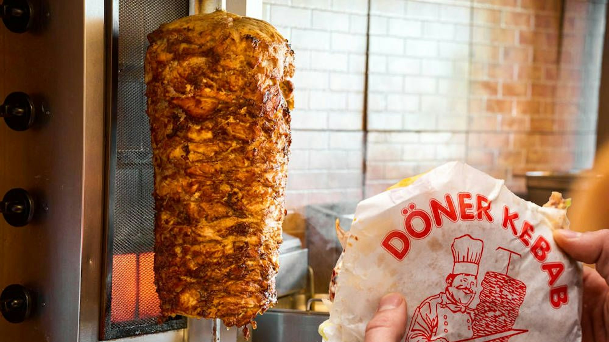 Das Foto zeigt einen Döner Kebab und einen mit Fleisch bestückten Dönerspieß.