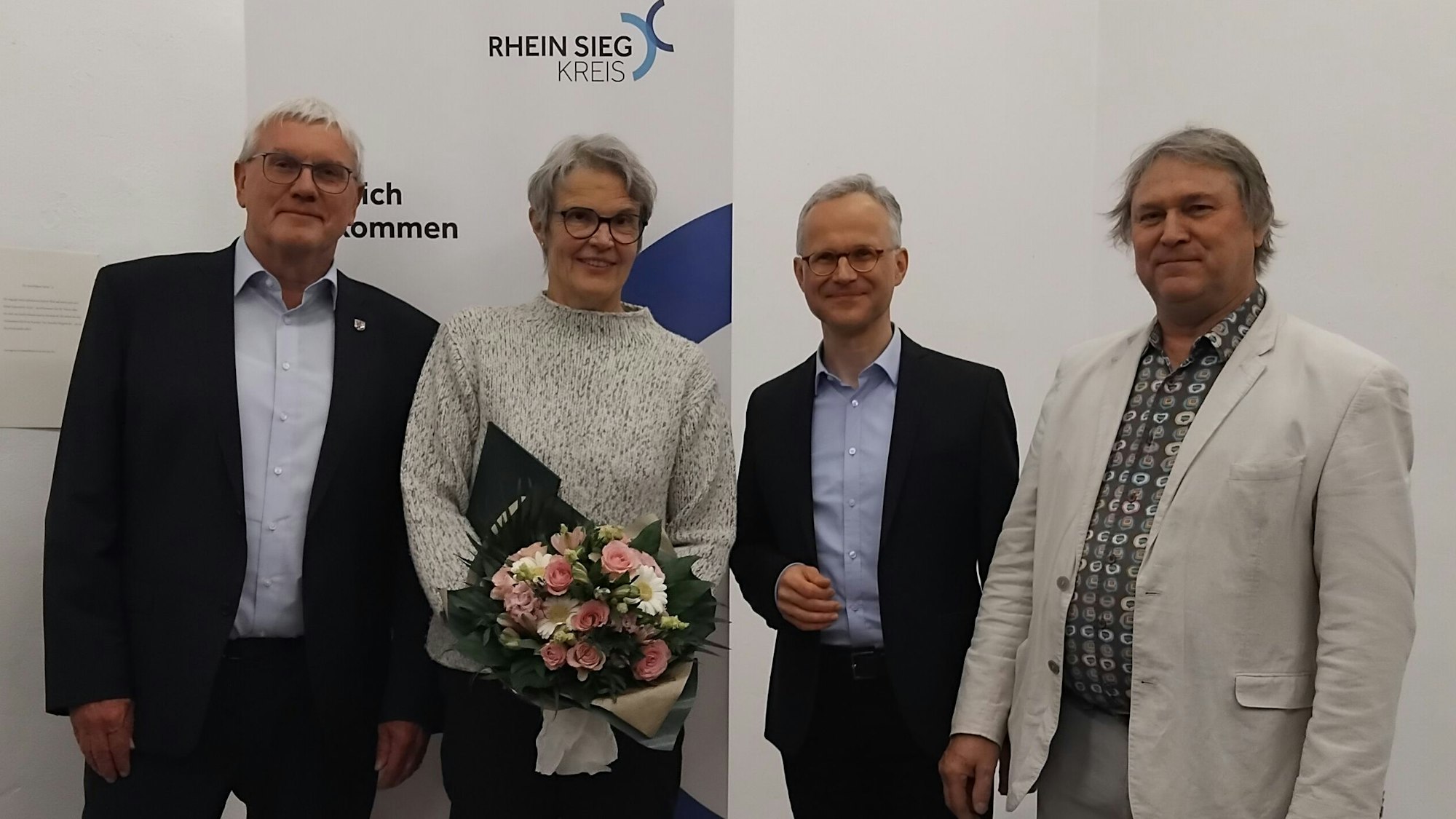 Drei Männer und eine Frau mit Blumenstrauß.