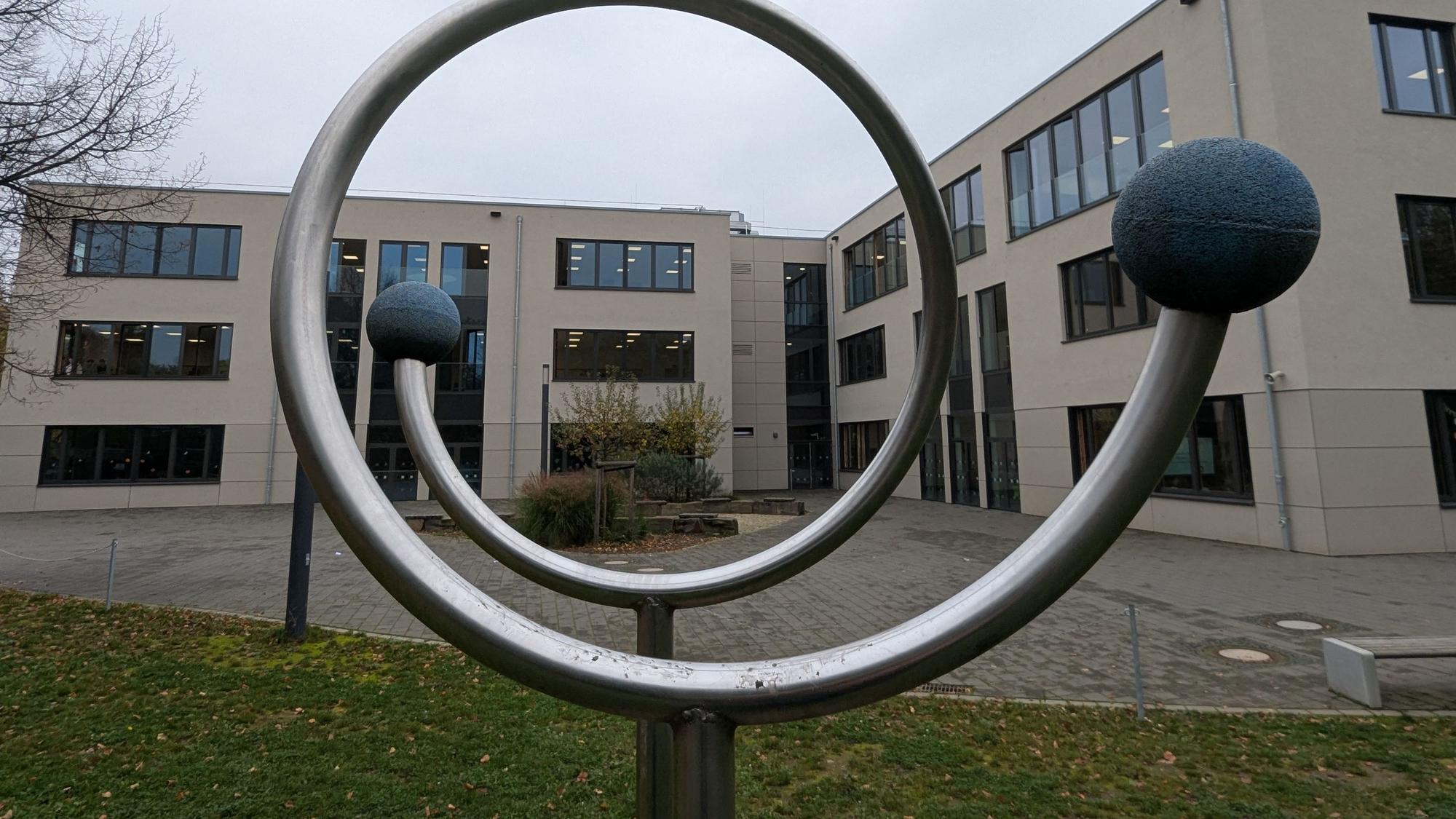 Das Foto zeigt eines der neuen Schulgebäude des Ernst-Mach-Gymnasiums hinter einem Sportgerät auf dem Schulhof.