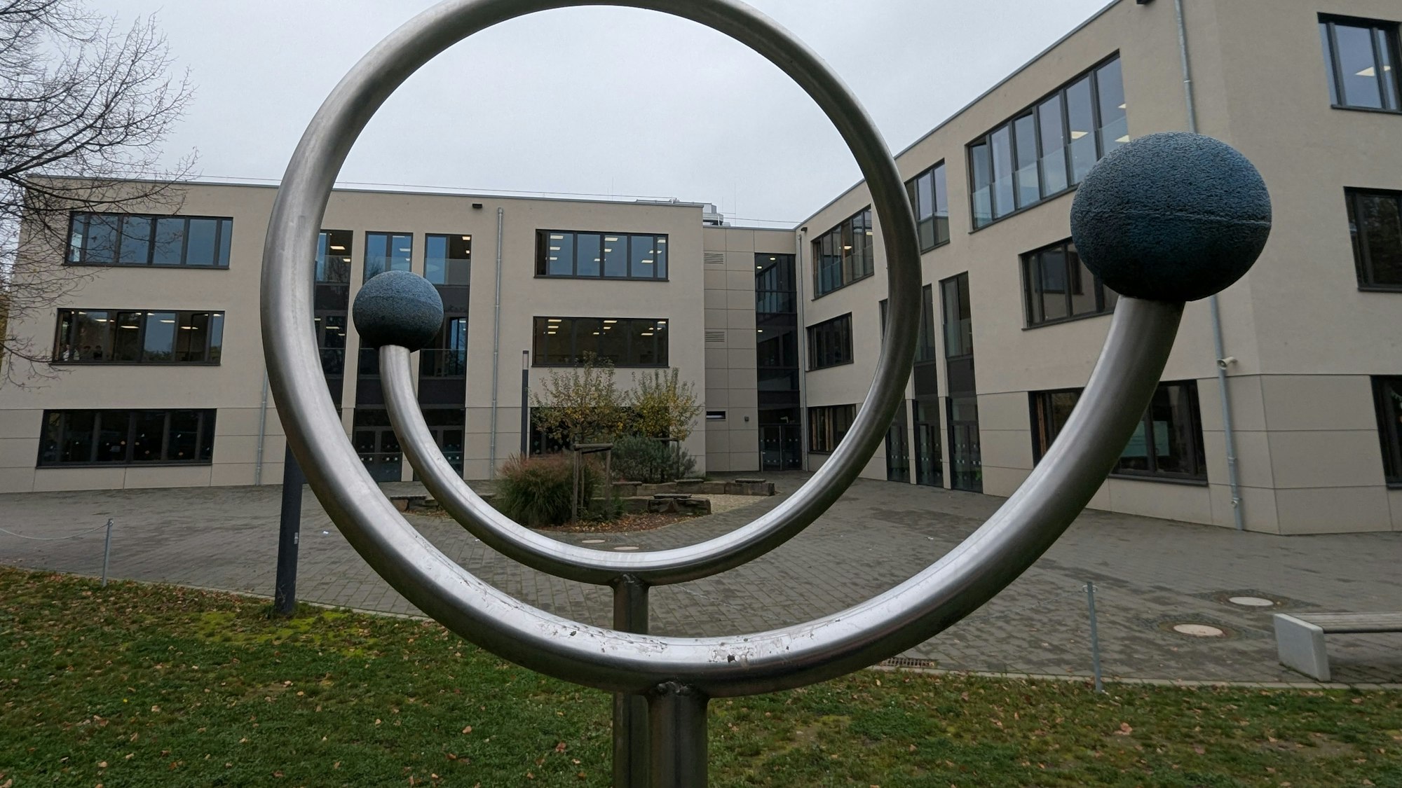 Das Foto zeigt eines der neuen Schulgebäude des Ernst-Mach-Gymnasiums hinter einem Sportgerät auf dem Schulhof.