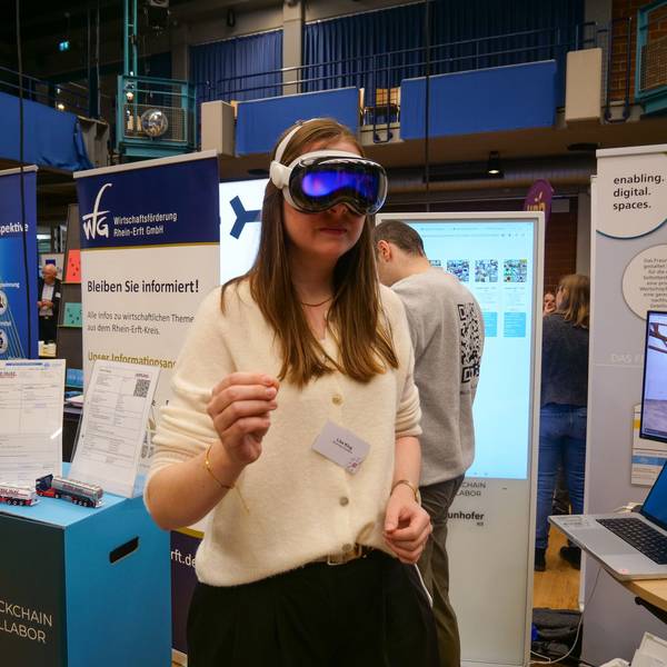 Das Foto zeigt eine Frau an einem Stand beim Wirtschaftstag, die eine VR-Brille trägt.