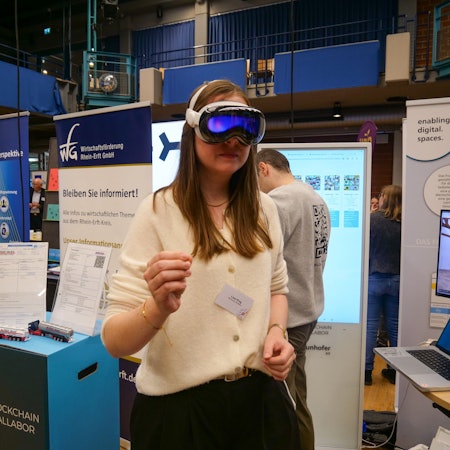 Das Foto zeigt eine Frau an einem Stand beim Wirtschaftstag, die eine VR-Brille trägt.