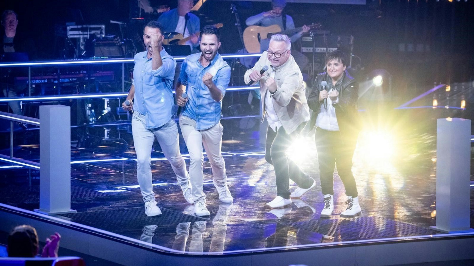 Vier Menschen singen auf einer Bühne.