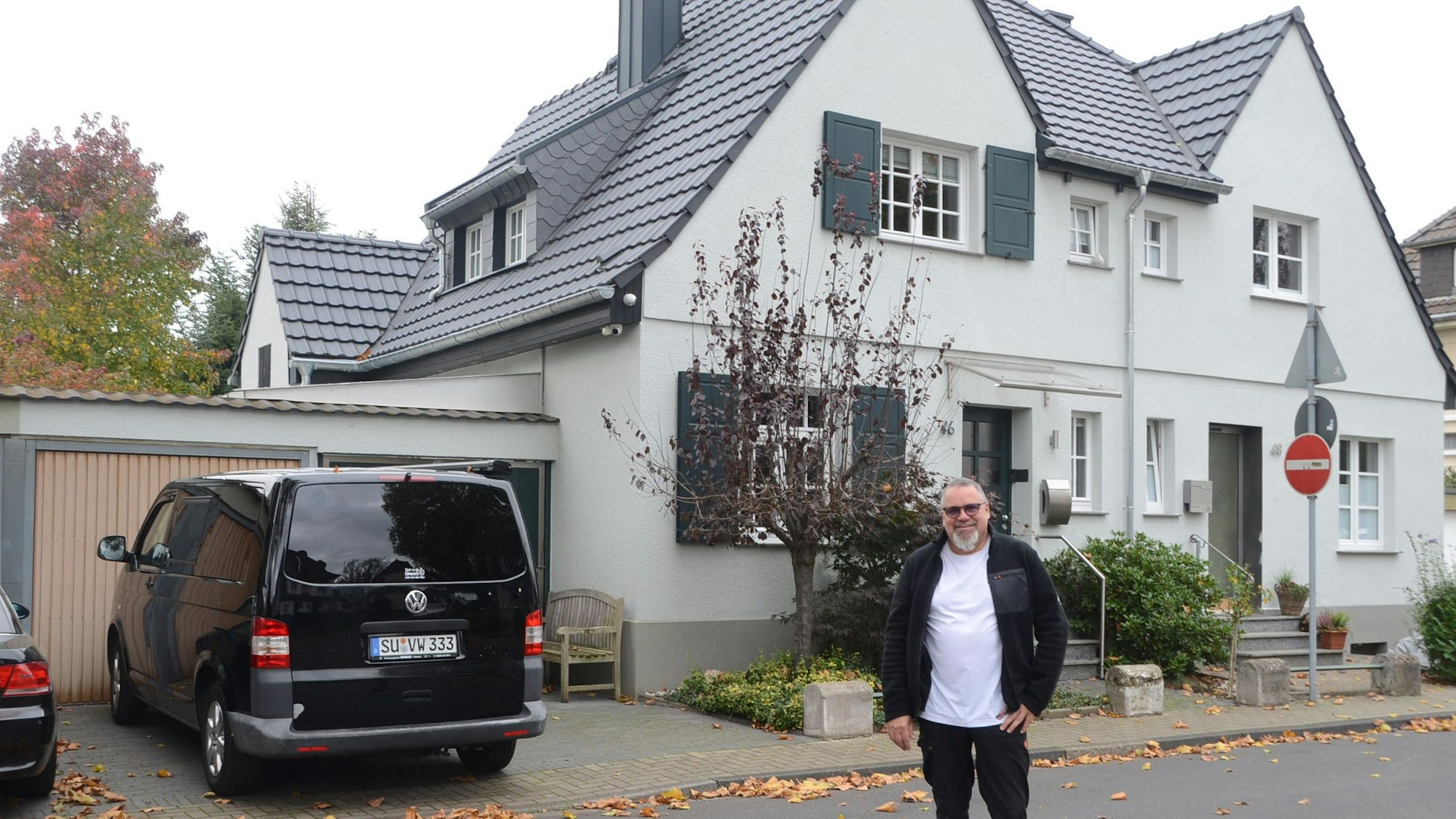 Ein Mann steht auf der Straße vor einer Doppelhaushälfte.