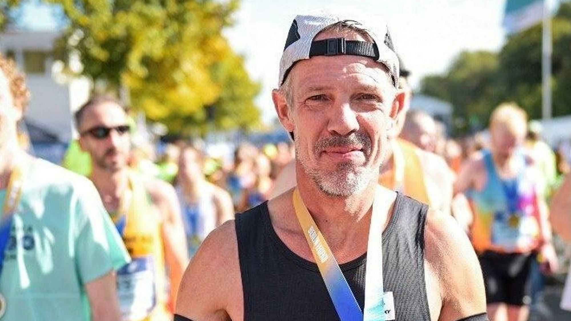 Markus Mey hat eine Medaille (nicht zu erkennen) um den Hals. Der Läufer trägt eine Kappe, die er mit dem Schirm nach hinten trägt.