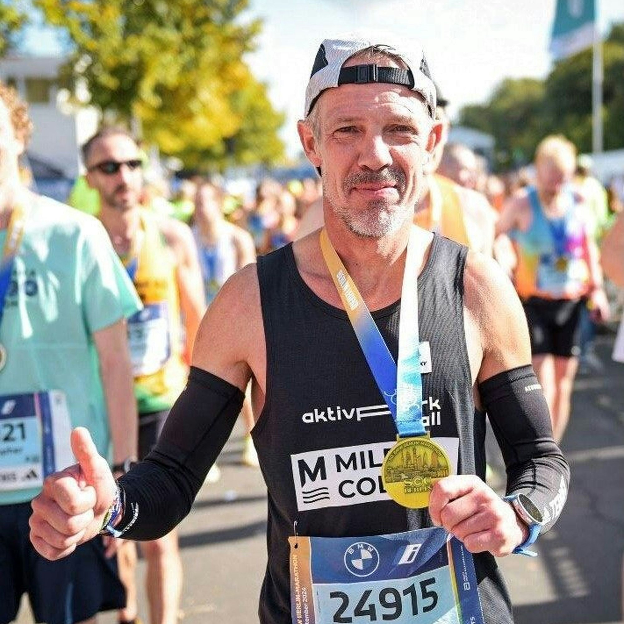 Markus Mey hält in einer Hand die Medaille, den Daumen der anderen Hand reckt er in die Höhe.