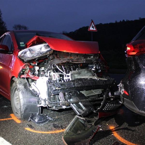 Ein schwer beschädigter roter Kia steht am Heck eines weiteren, ebenfalls beschädigten Fahrzeugs auf der Altenberger-Dom-Straße in Odenthal.
