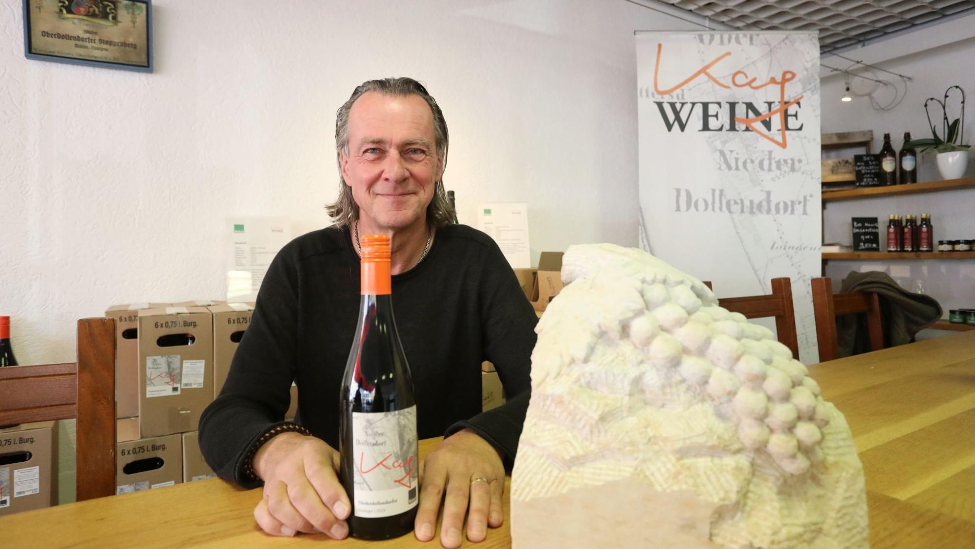 Wein im Siebengebirge, Winzer Kay Thiel zeigt eine Weinflasche.