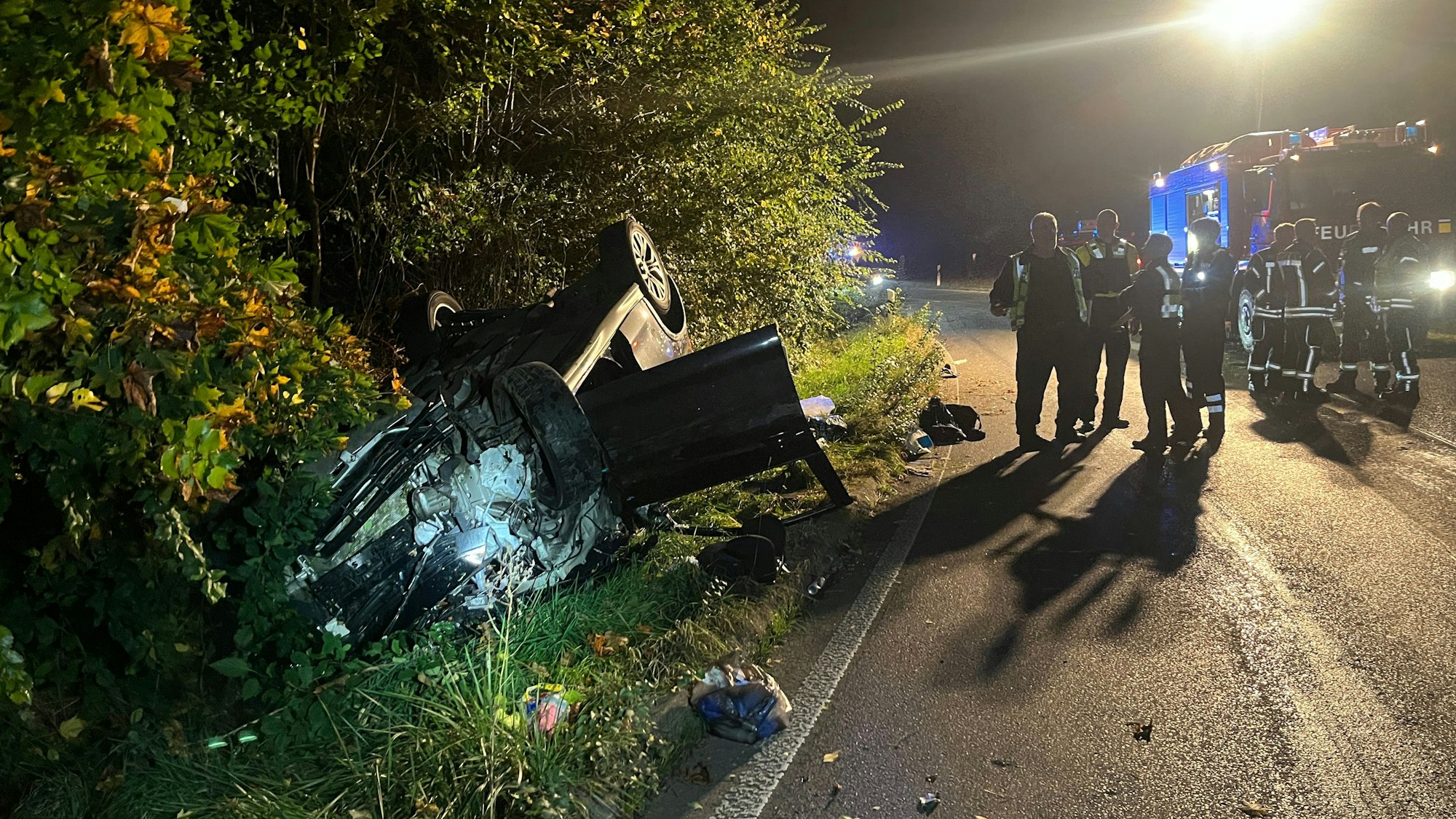 Ein Auto liegt neben der Fahrbahn auf dem Dach.