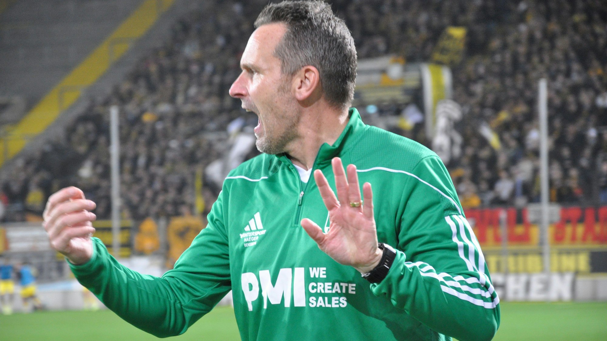 Das Foto zeigt einen Fußballtrainer in grüner Trainingsjacke.