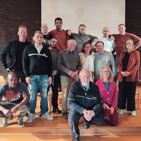 15 Leute verschiedenen Alters stehen für ein Gruppenfoto zusammen.