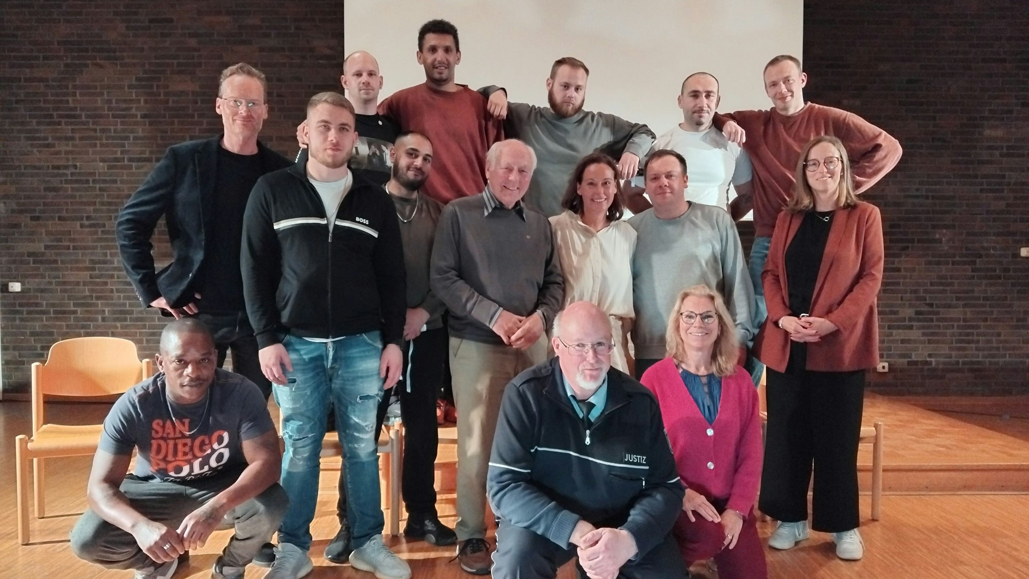 15 Leute verschiedenen Alters stehen für ein Gruppenfoto zusammen.