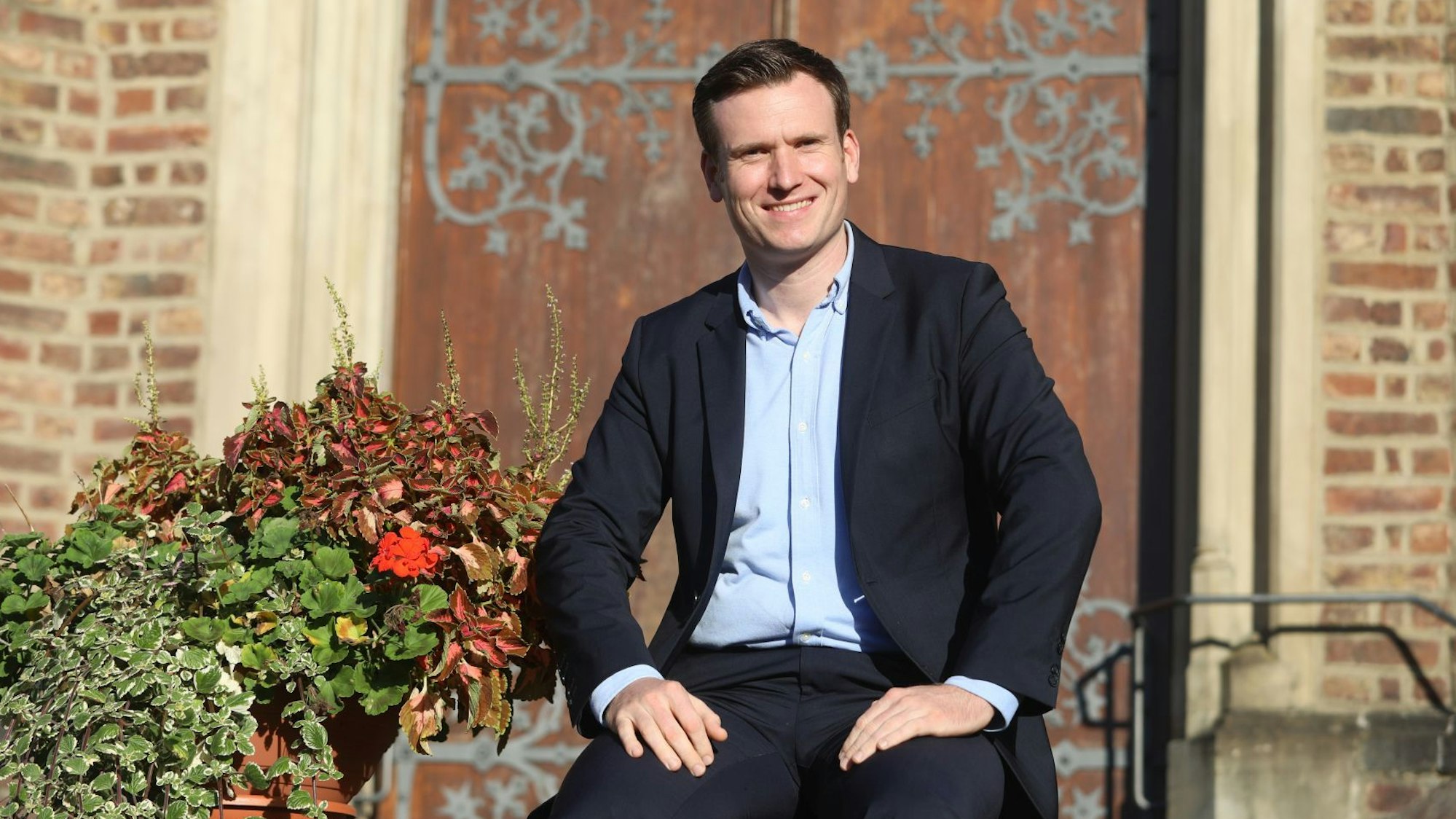 Ein Mann sitzt vor einer Kapelle mit einer schweren Holztür.