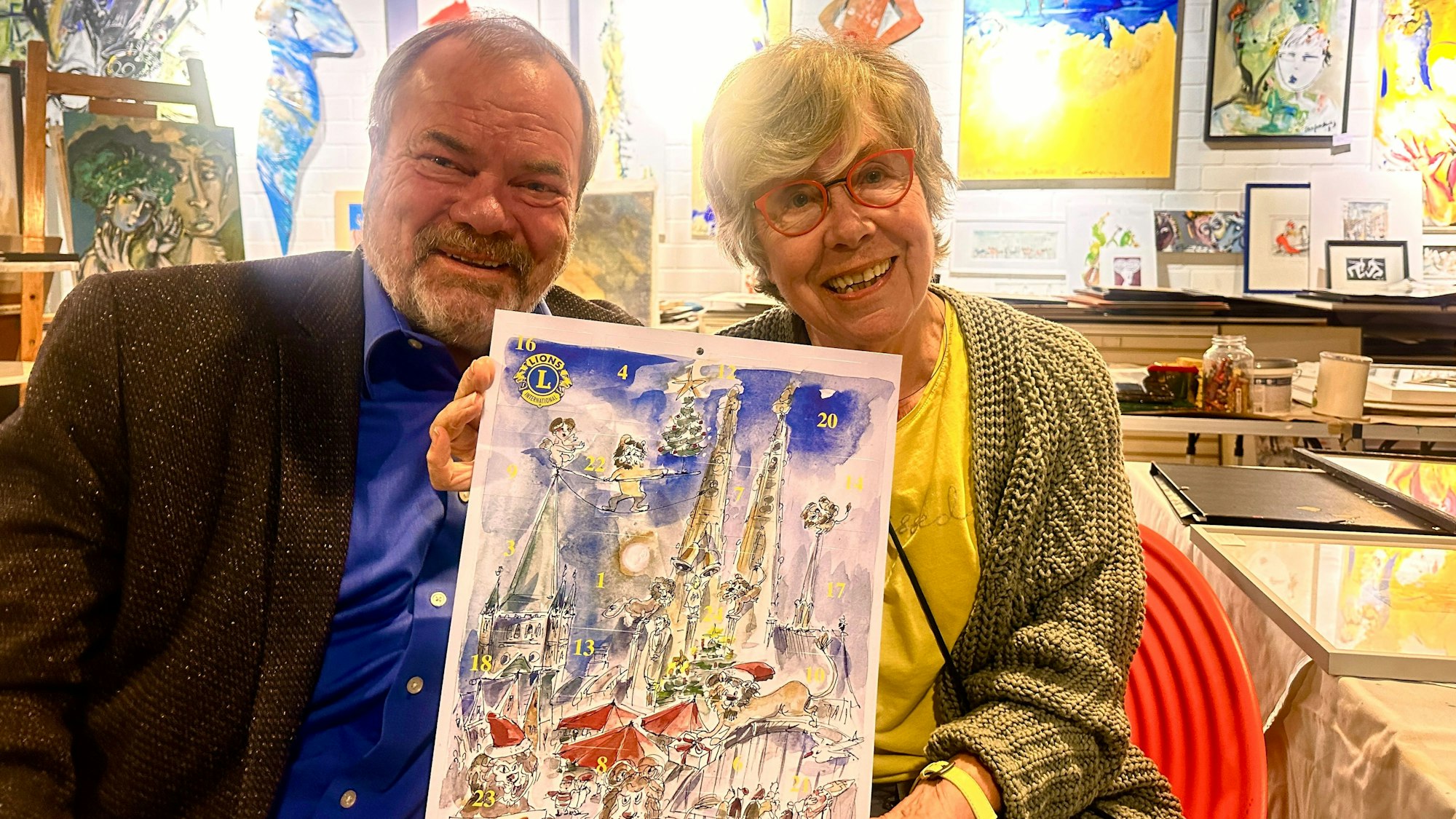 Ingo Sieger vom Lions Club Köln-Albertus Magnus und Gerda Laufenberg stellen den neuen Kalender vor, der Karneval mit Advent verbindet.