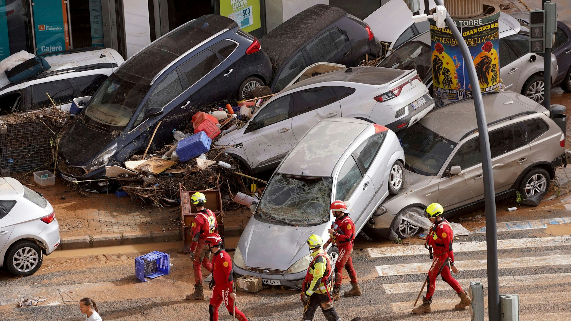 Rettungskräfte gehen an aufgestapelten Autos vorbei, die von den Überschwemmungen weggeschwemmt wurden.
