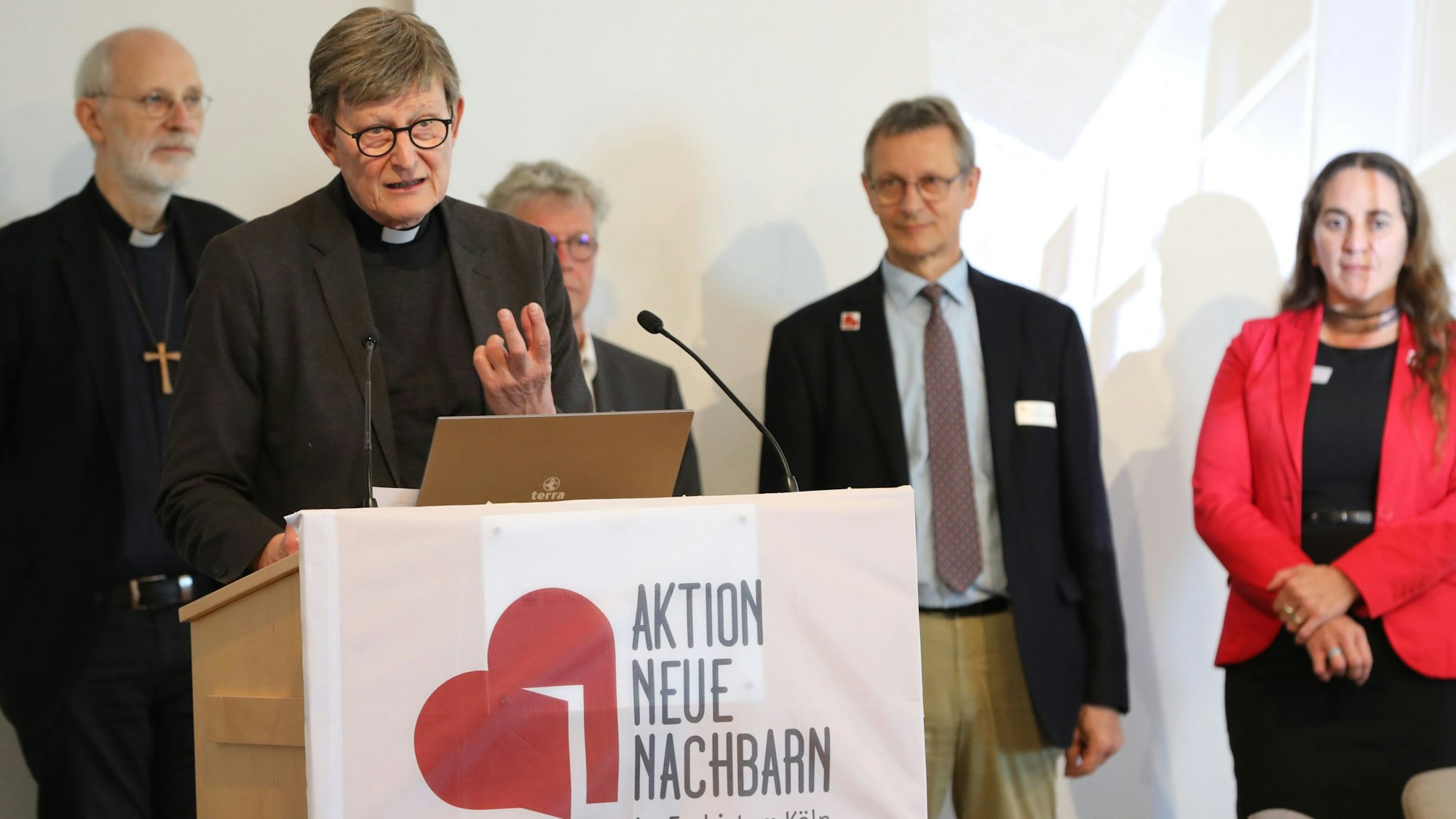 Ein Redner am Pult, vier Menschen hinter ihm auf der Bühne