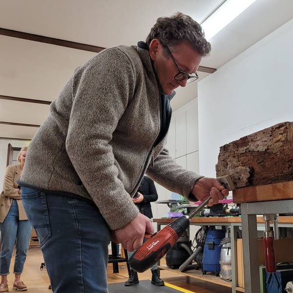 Ein Mann bohrt einen Holzbalken an.