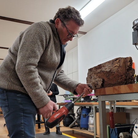 Ein Mann bohrt einen Holzbalken an.