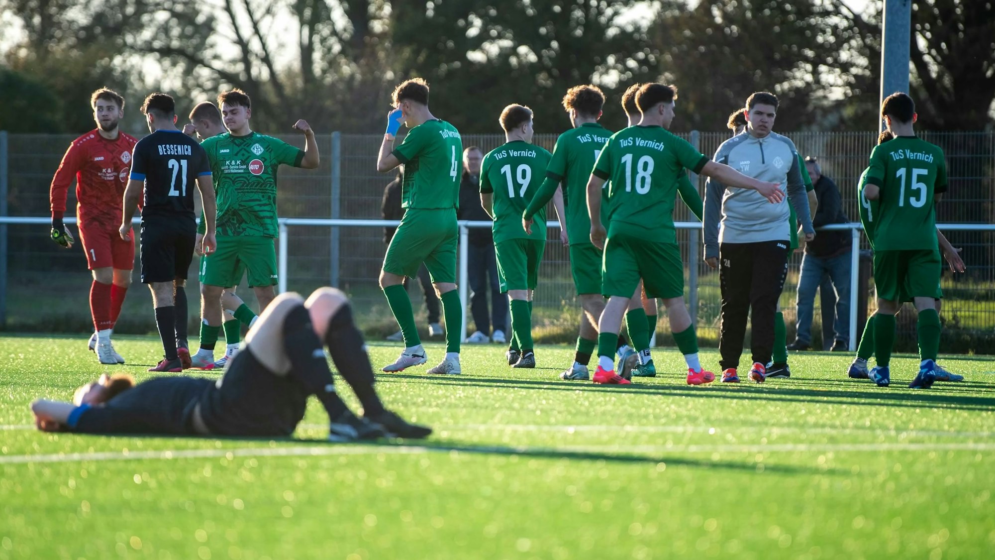 Das Bild zeigt zahlreiche Fußballer in grünen Trikots, die sich über ein Tor freuen. Ein Gegenspieler liegt auf dem Boden.