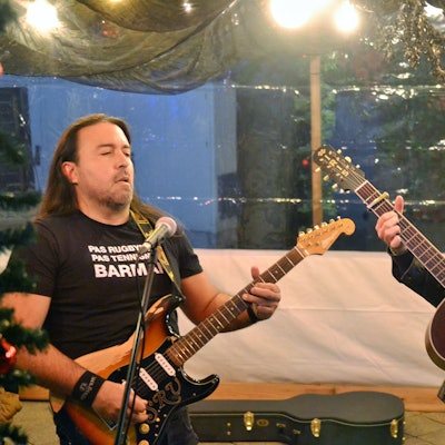 Zwei Männer spielen Gitarren hinter Mikrofonen und schauen sich an.