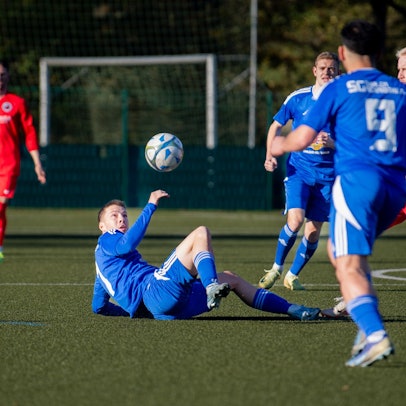 Das Bild zeigt den Spieler der SG Dahlem-Schmidtheim, wie er auf dem Rücken liegend den Ball spielt.