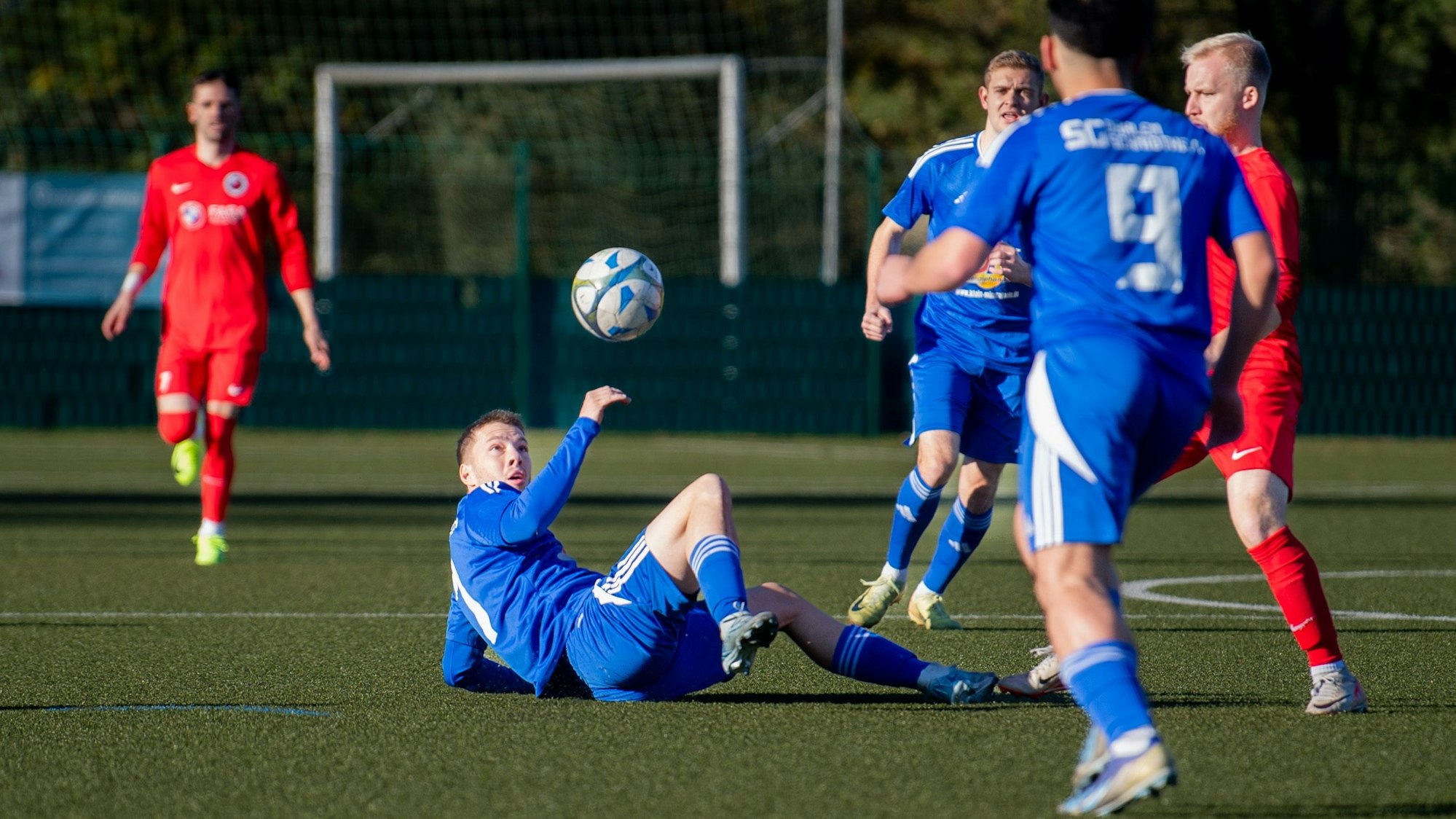 Das Bild zeigt den Spieler der SG Dahlem-Schmidtheim, wie er auf dem Rücken liegend den Ball spielt.
