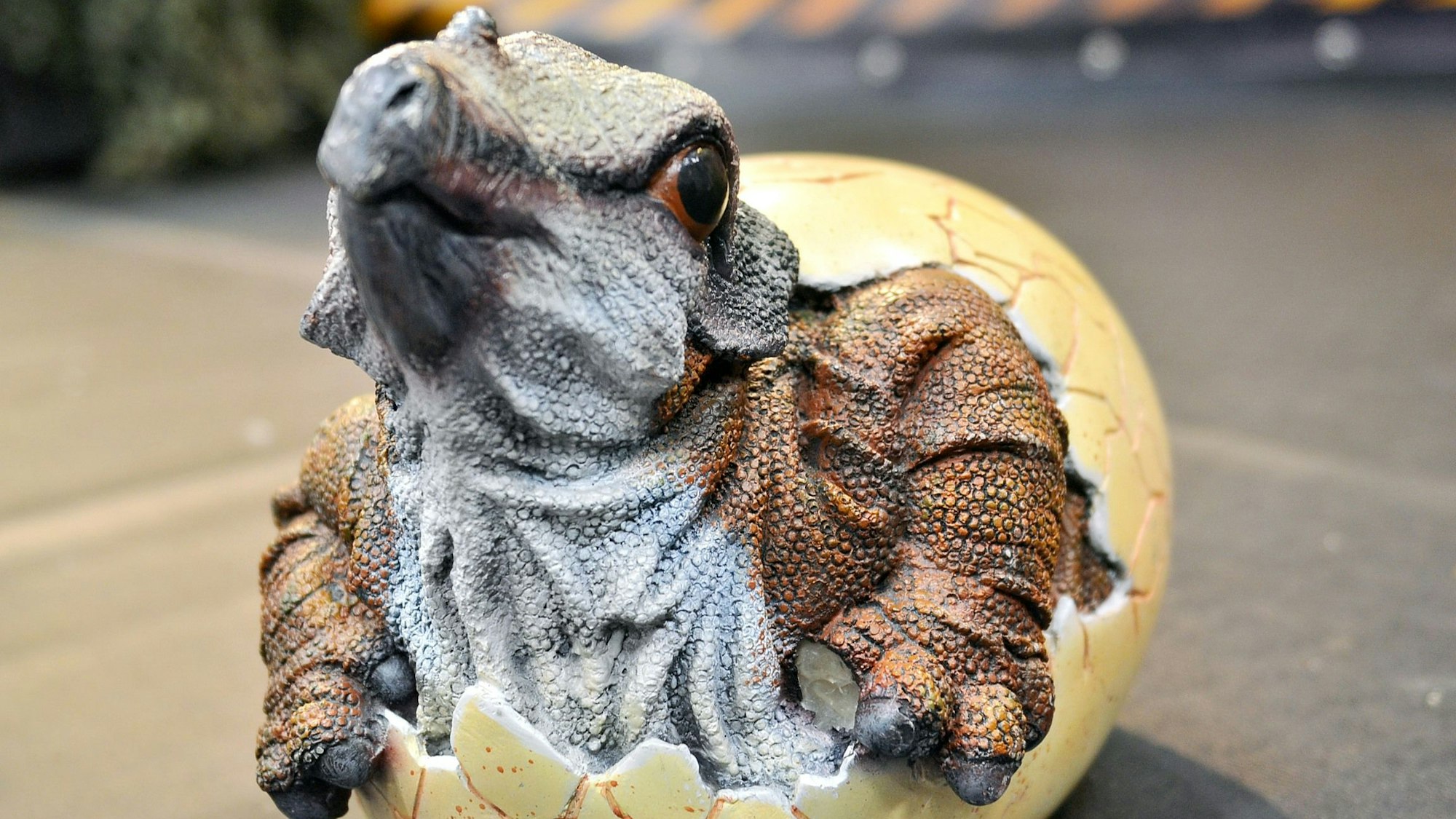 Eine Dino-Figur zeigt das Dinobaby beim Schlüpfen aus einem Ei.