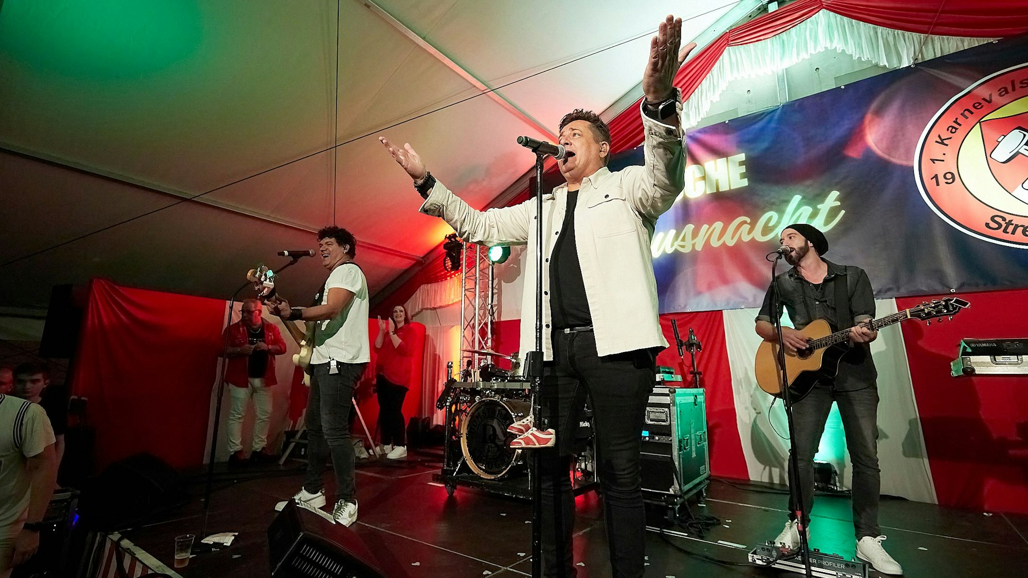 Die Band Domstürmer spielt auf einer Bühne. Der Sänger Micky Nauber breitet seine Arme in Richtung des Publikums aus.