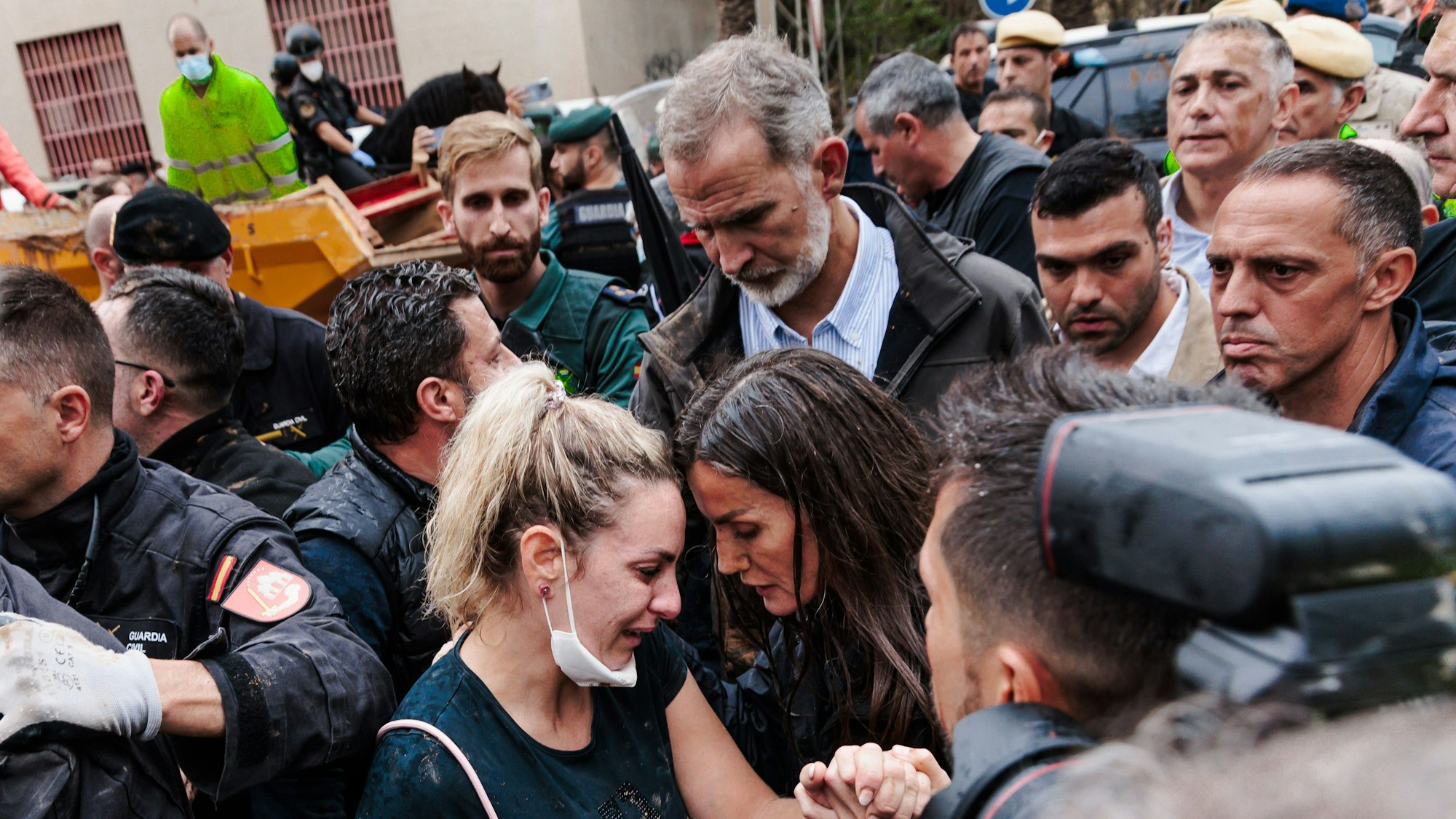 König Felipe VI. (Mitte) und Königin Letizia (Mitte unten) von Spanien sprechen bei ihrem Besuch in einem von den Überschwemmungen betroffenen Gebiet mit Menschen.