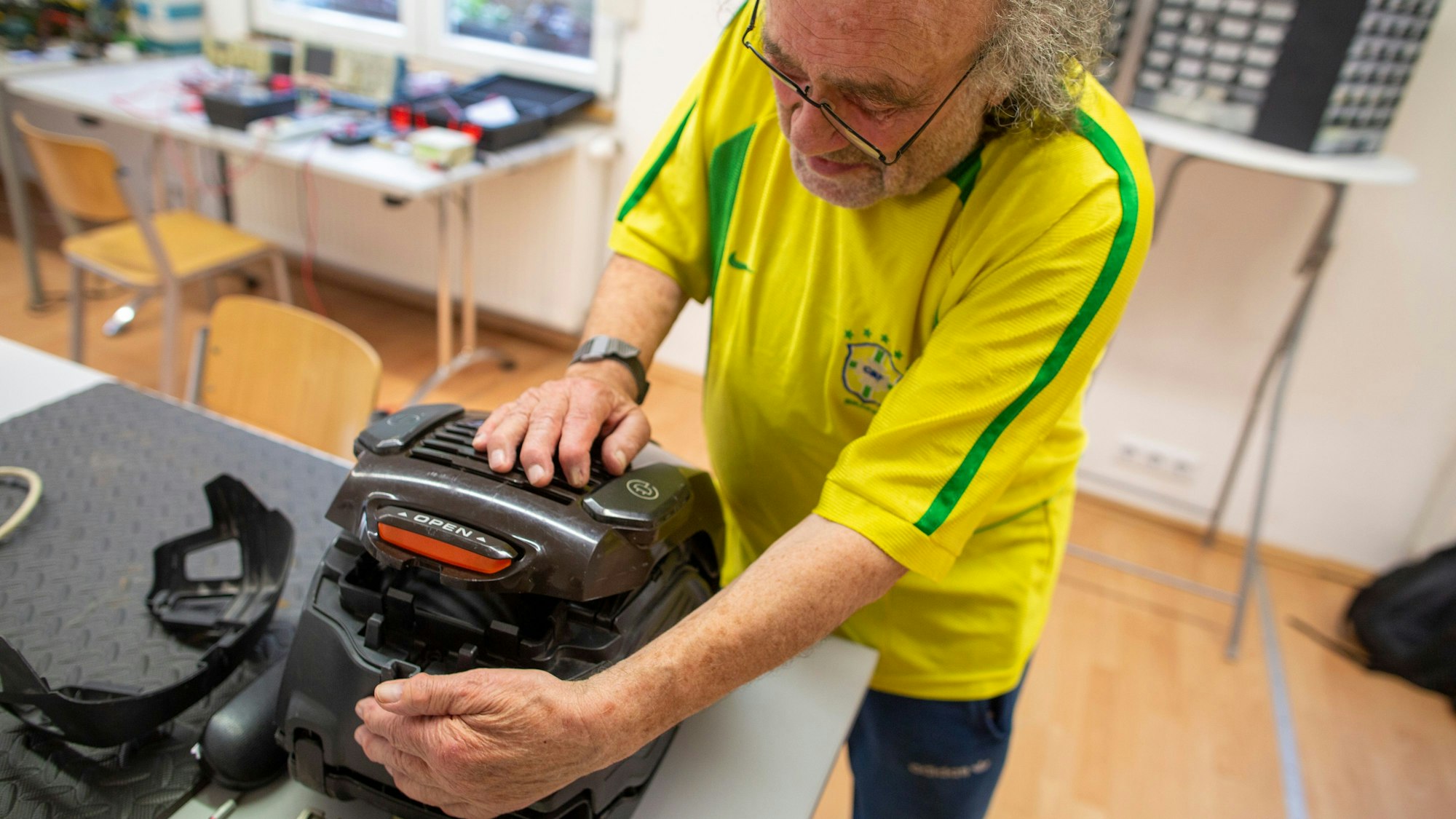 Ein Mann in gelbem Fußballtrikot schließt einen Staubsauger. © Thomas Banneyer