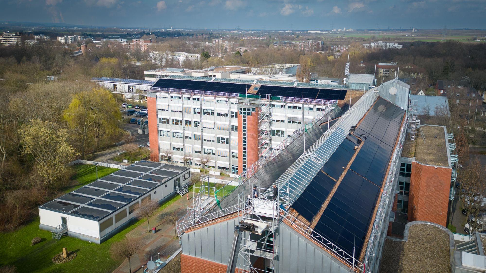 Die Luftaufnahme zeigt die Solarmodule auf den Schrägflächen des Rathausdachs.
