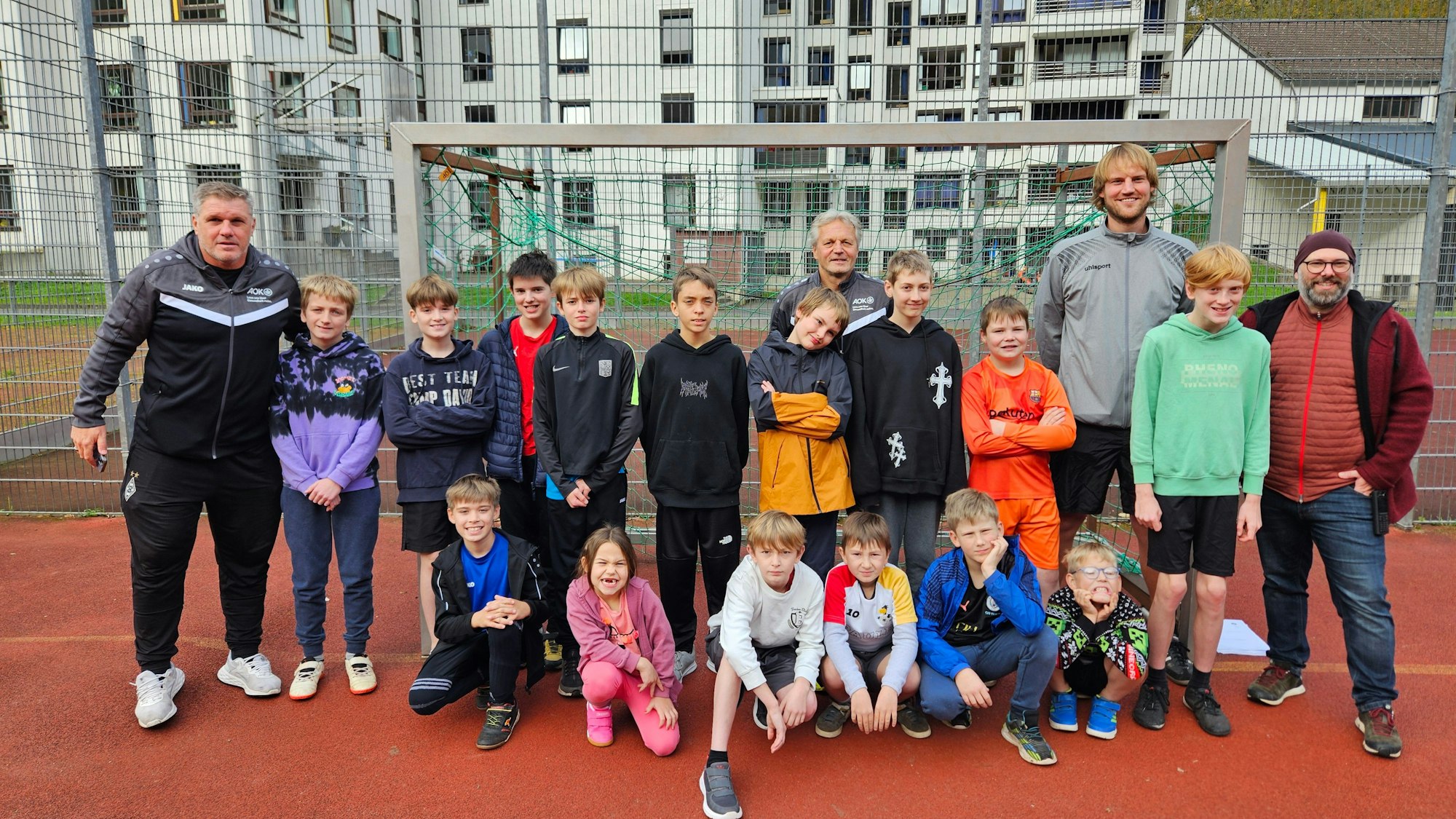 Die Ex-Fußballprofis Michael Klinkert und Marcel Witecek stehen mit den Kindern und zwei Lehrern an einem Tor.