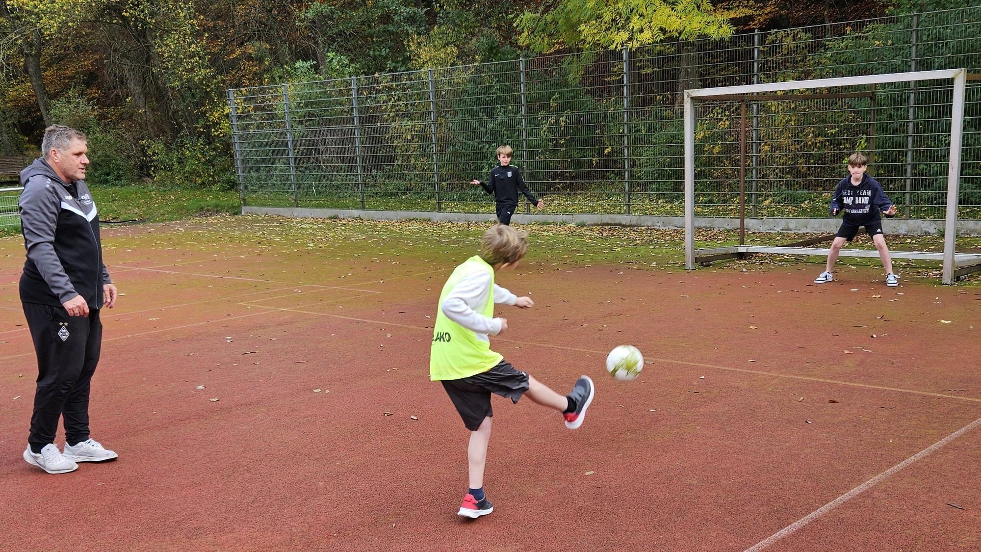 Ex-Fußballprofi Michael Klinkert schaut zu, während ein Junge auf das Tor schießt.