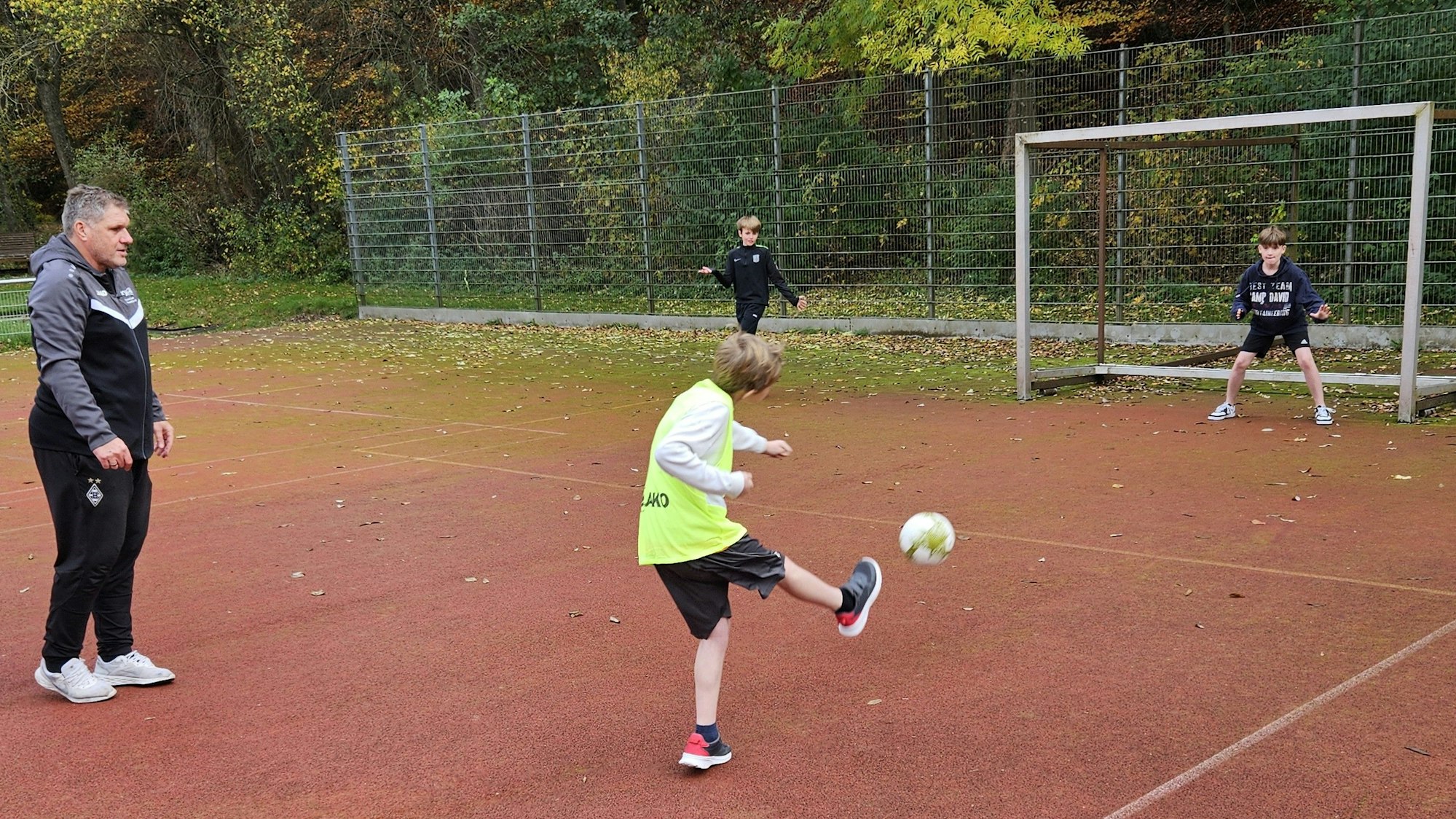 Ex-Fußballprofi Michael Klinkert schaut zu, während ein Junge auf das Tor schießt.