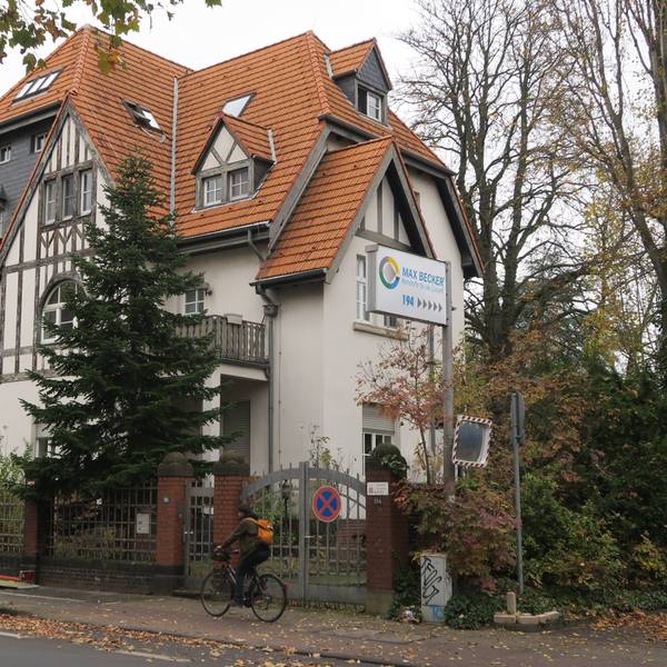 Blick auf ein Tor und ein Schild, das den Eingang zum Max-Becker-Areal markiert.