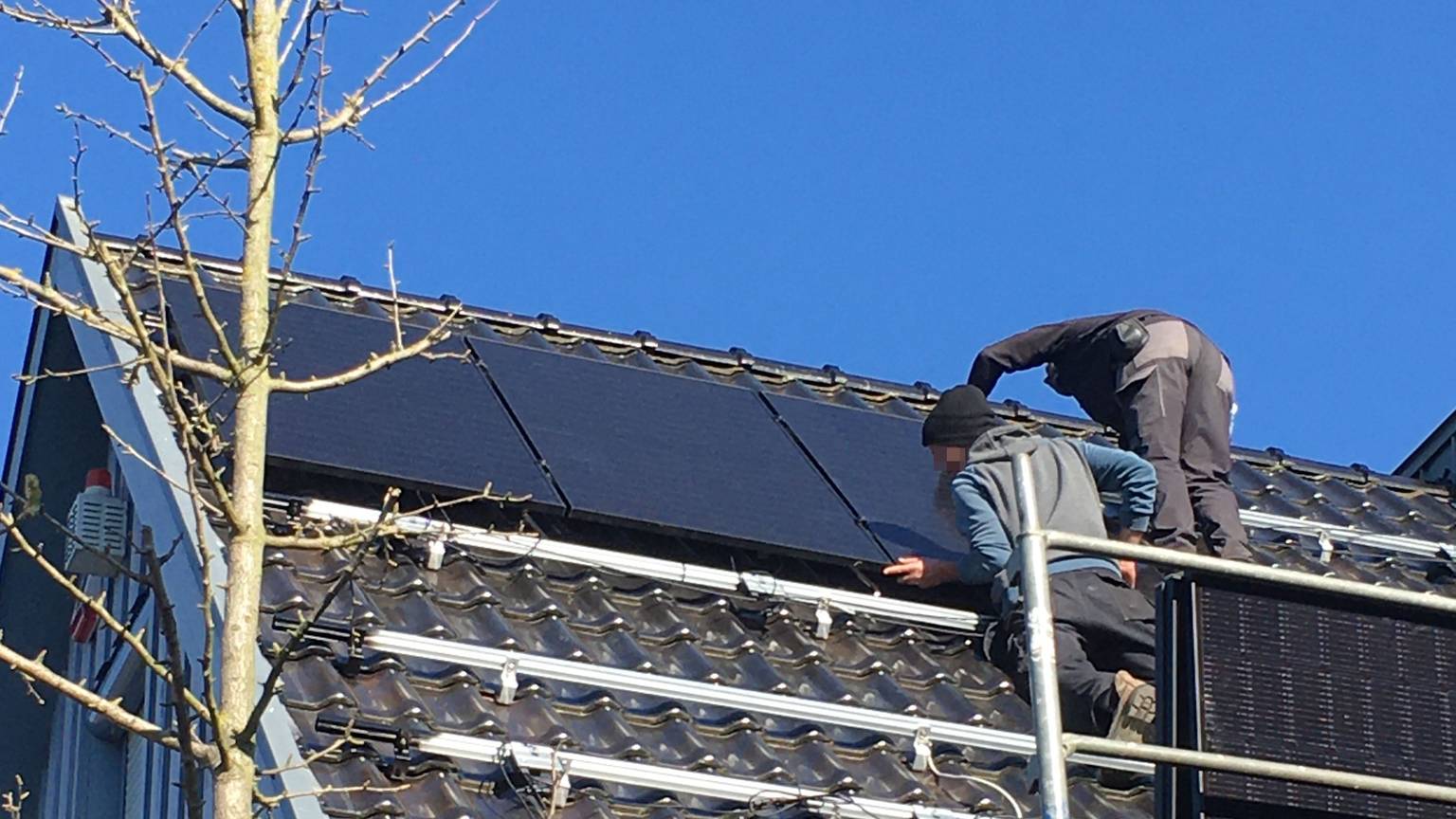 Die Männer befestigen ein Photovoltaik-Modul auf der Unterkonstruktion.