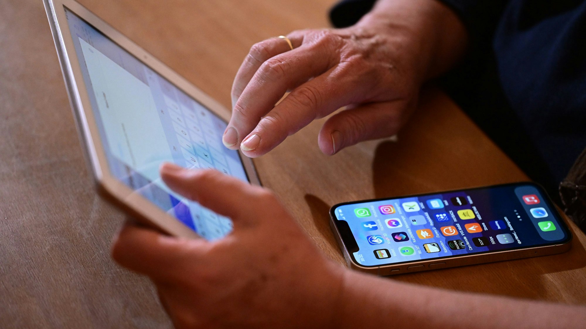Eine Frau tippt auf einem iPad eine Mail (gestellte Szene).