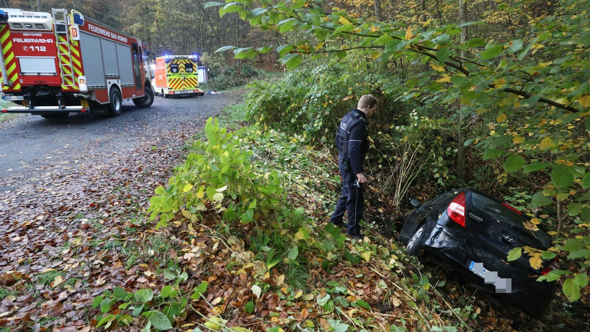 Ein Polizist steht neben einem Auto, das in den Straßengraben gerutscht ist.