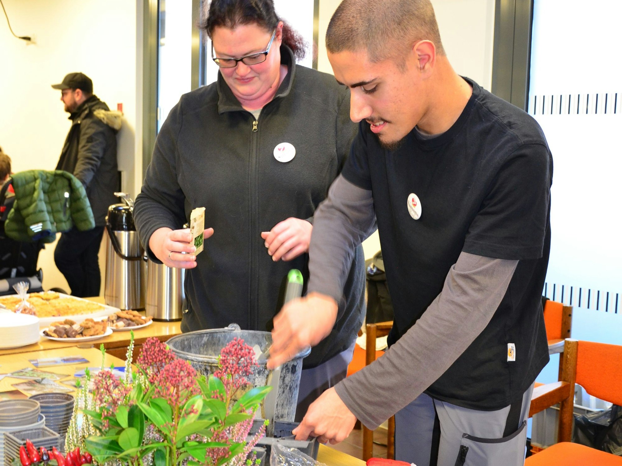 Das Foto zeigt einen jungen Mann beim Pflanzen von Blumen.