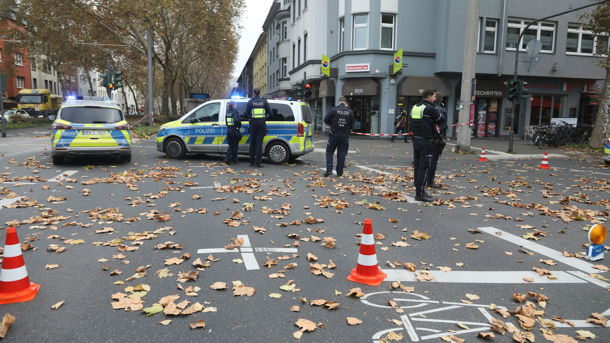Auf einer Straßenkreuzung stehen zwei Polizeiautos und mehrere Polizisten.