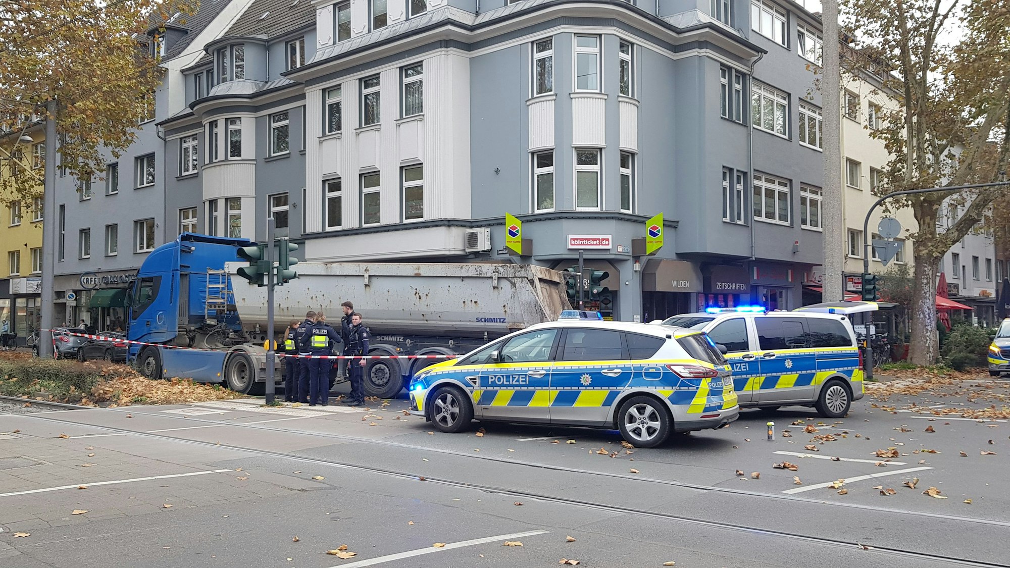Zwei Polizeiautos stehen an einer Kreuzung, ein Kipplaster steht auf dem Gehweg. Die Polizei hat die Unfallstelle abgesperrt.