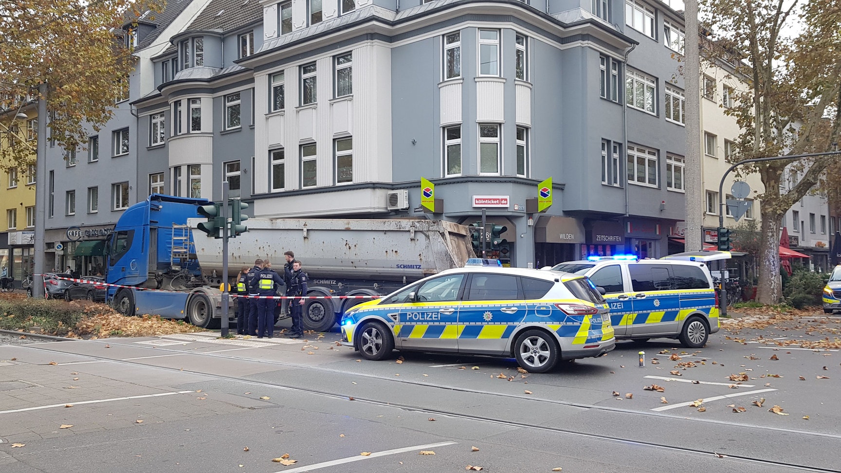 Zwei Polizeiautos stehen an einer Kreuzung, ein Kipplaster steht auf dem Gehweg. Die Polizei hat die Unfallstelle abgesperrt.