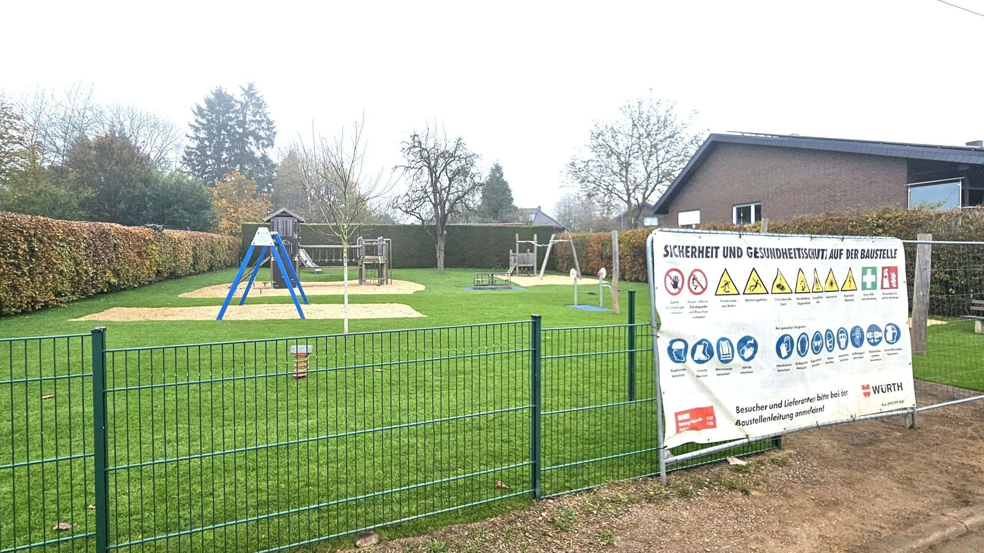 Zu sehen sind der neue Spielplatz an der Römerstraße und ein Warnplakat am Zaun.