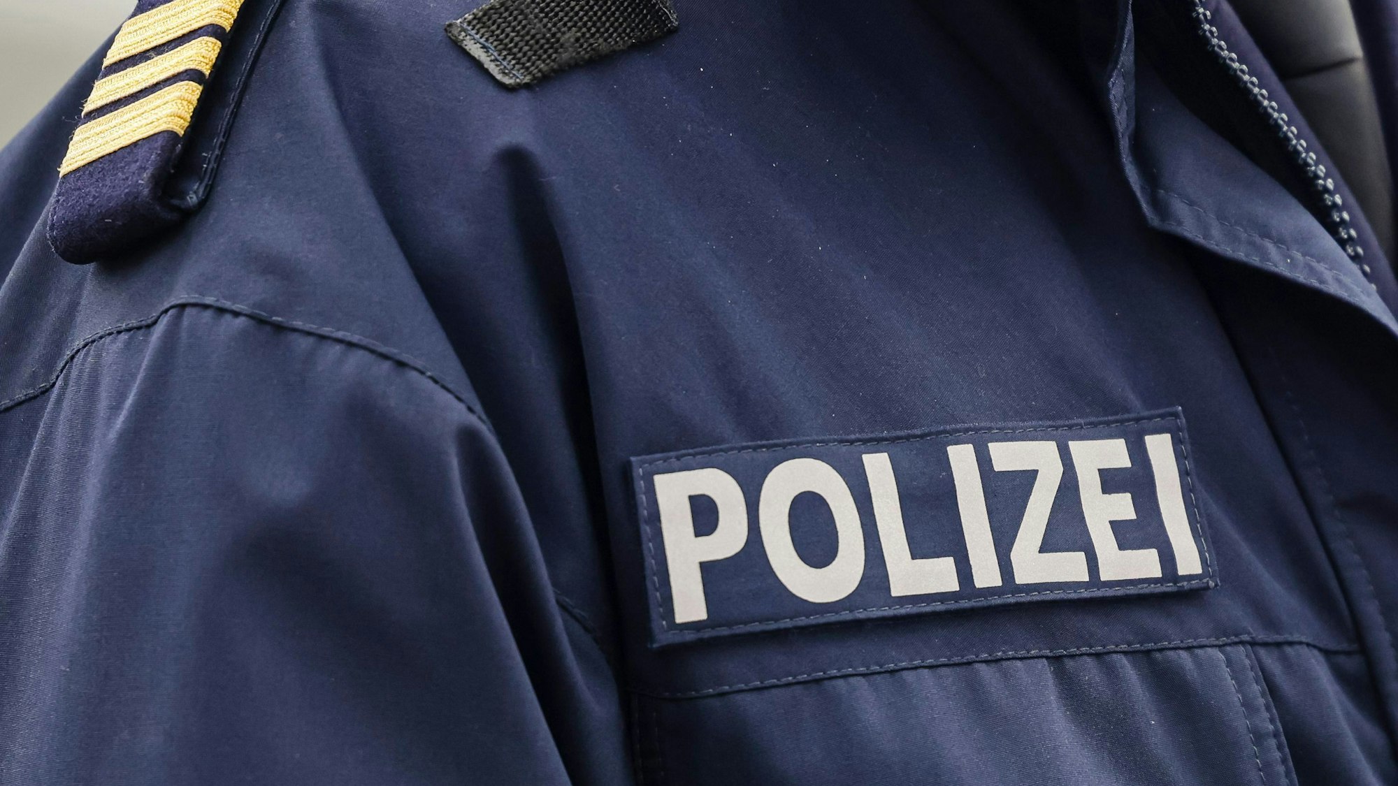 Ein Aufnäher der Polizei ist an einer Jacke angebracht.