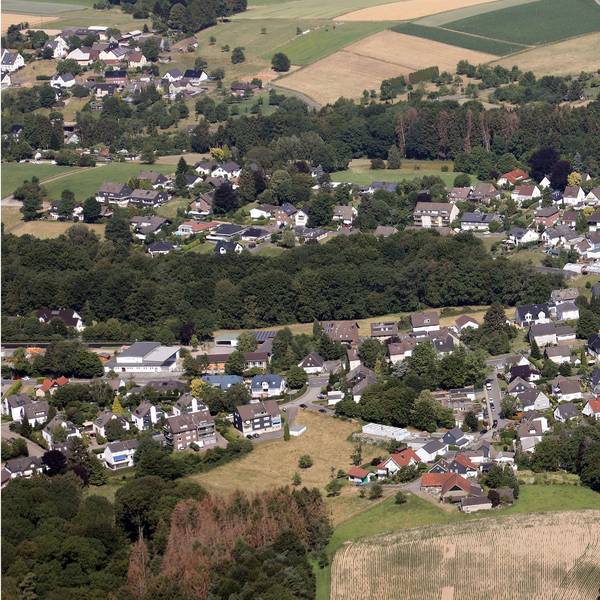 Ein Luftbild von Odenthal-Blecher. Man sieht den zentralen Kreisverkehr, links davon die Bergstraße und im unteren Bildteil die Serperntinen nach Altenberg.