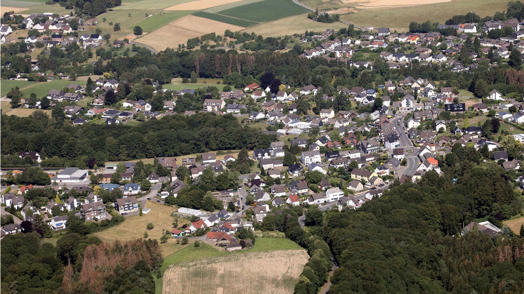 Ein Luftbild von Odenthal-Blecher. Man sieht den zentralen Kreisverkehr, links davon die Bergstraße und im unteren Bildteil die Serperntinen nach Altenberg.